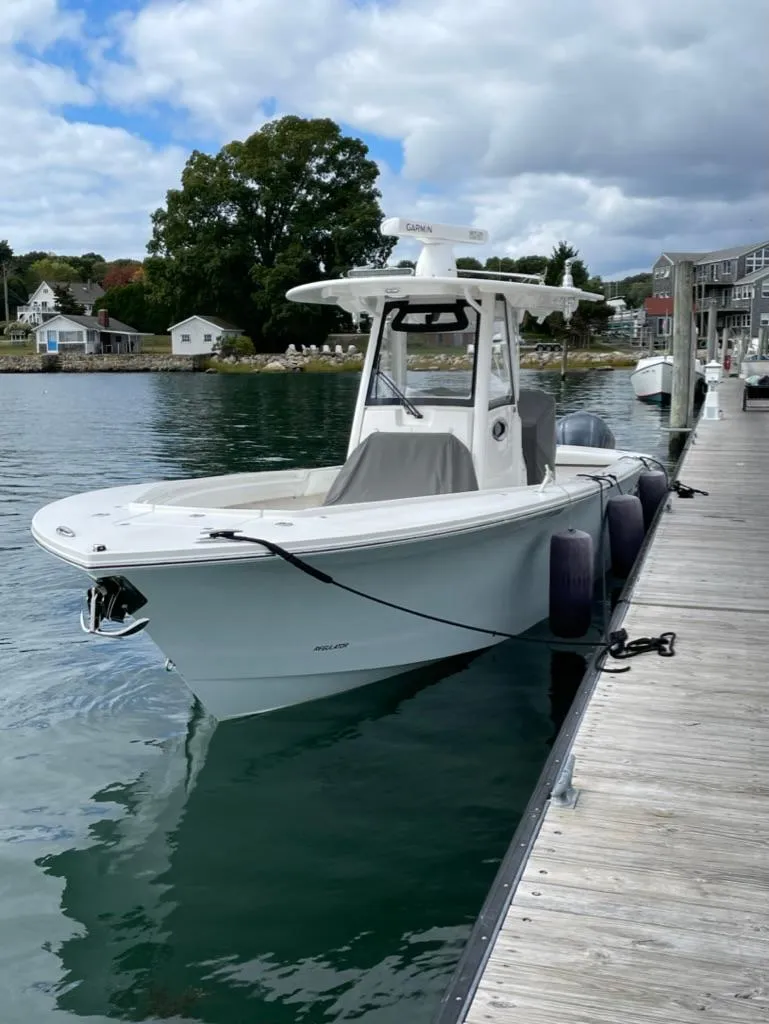 Slide: The Image of 2021 Regulator 28 boat docked on calm water under a cloudy sky. - 5
