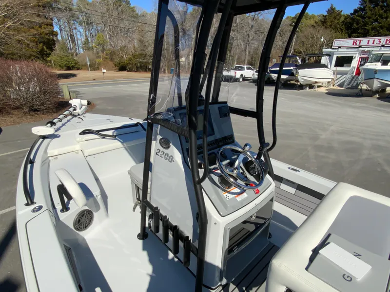 Slide: The Image of 2023 Pathfinder 2200 TRS boat interior with steering console and seating in a marina setting. - 30