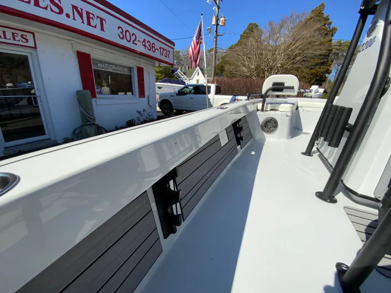 Slide: The Image of 2023 Pathfinder 2200 TRS boat interior with seating and storage, near a sales building. - 49