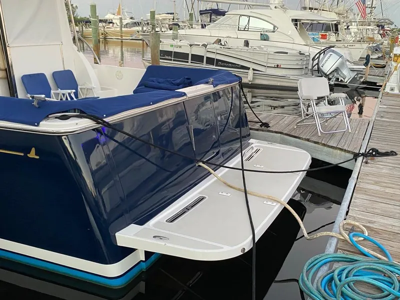 Slide: The Image of 2014 Back Cove 41 yacht docked, featuring a sleek blue exterior and spacious swim platform. - 7