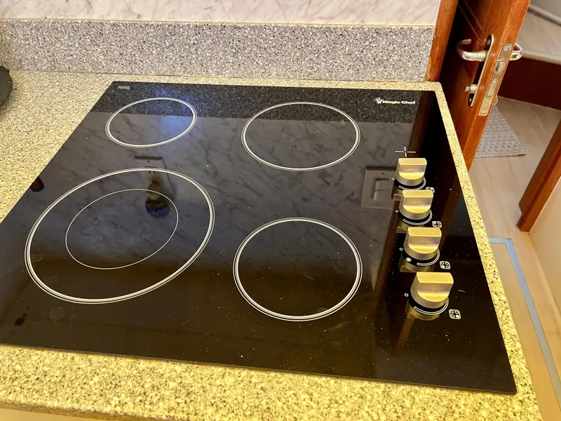 Slide: The Image of Electric stovetop with four burners and control knobs on a granite countertop. - 48