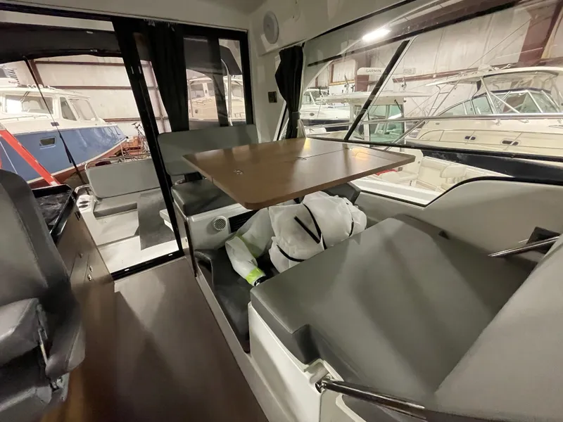 Slide: The Image of Interior of 2022 Beneteau Antares 9 boat, featuring seating and table in a marina setting. - 30