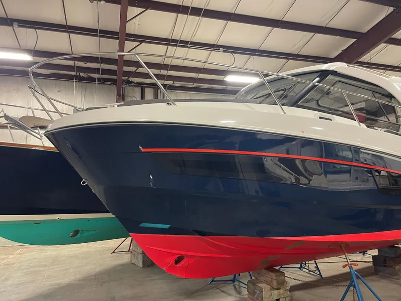 Slide: The Image of 2022 Beneteau Antares 9 boat in indoor storage, featuring sleek blue and red hull design. - 5