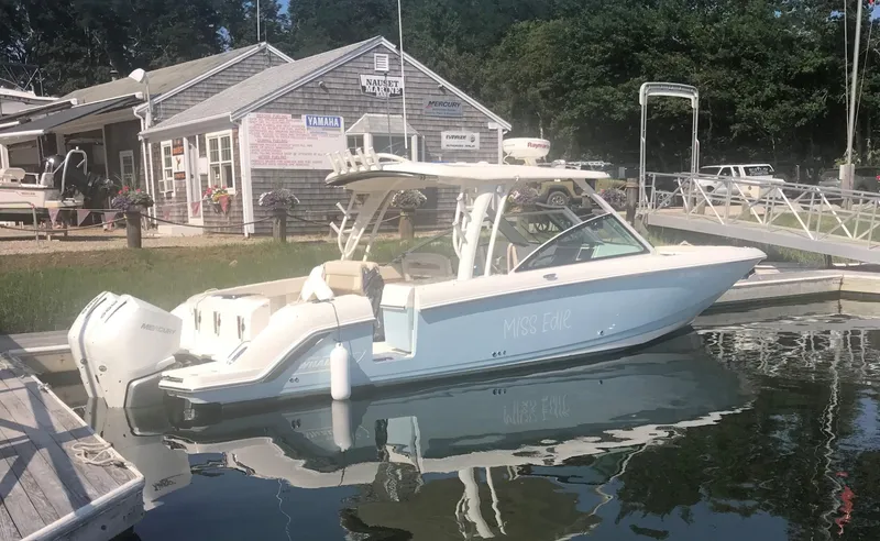 The Image of 2021 Boston Whaler 320 Vantage docked at marina, reflecting on calm water. - 0