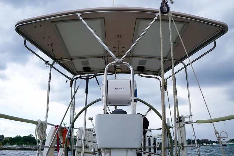 Slide: The Image of 2001 J Boats J/42 sailboat helm with canopy, ropes, and wheel, under cloudy sky. - 18