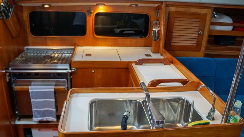 Slide: The Image of 2001 J Boats J/42 yacht interior kitchen with sink, stove, and wooden cabinetry. - 21