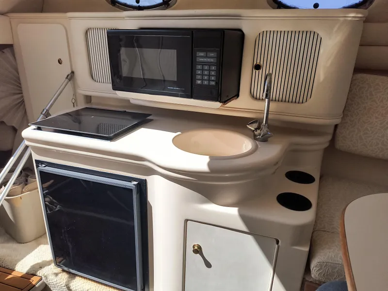 Slide: The Image of 2001 Sea Ray 260 Sundancer boat kitchenette with microwave, sink, and mini-fridge. - 15