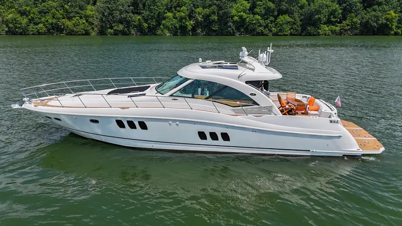 Slide: The Image of 2007 Sea Ray 60 Sundancer yacht cruising on a serene lake with lush green shoreline. - 10