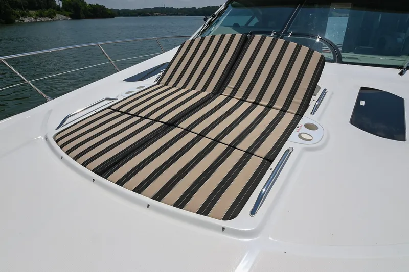 Slide: The Image of 2007 Sea Ray 60 Sundancer with striped sunbed on deck, overlooking serene waters. - 24