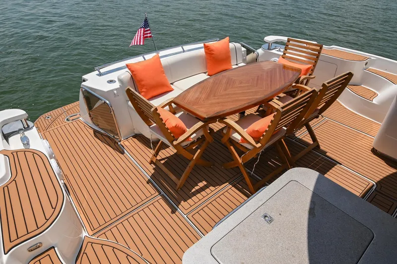 Slide: The Image of Luxury deck of 2007 Sea Ray 60 Sundancer with wooden table and orange cushions. - 29