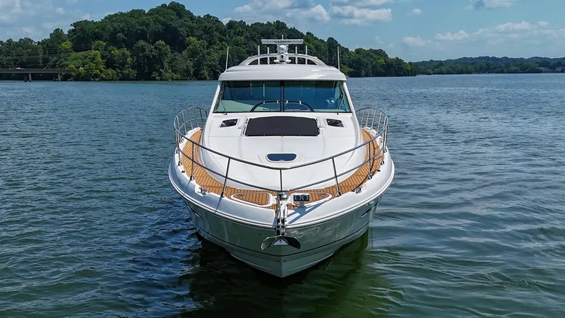 Slide: The Image of 2007 Sea Ray 60 Sundancer yacht on a serene lake with lush green shoreline. - 8