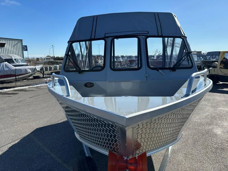 Slide: The Image of 2025 Hewescraft 160 Sportsman boat, front view, parked outdoors on a sunny day. - 2