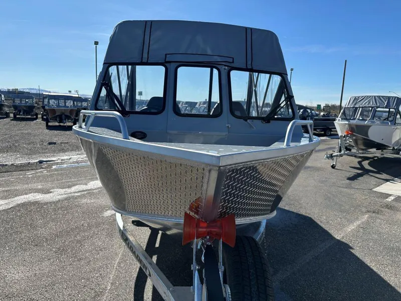 Slide: The Image of 2025 Hewescraft 180 Sportsman boat on trailer, parked outdoors under clear blue sky. - 2