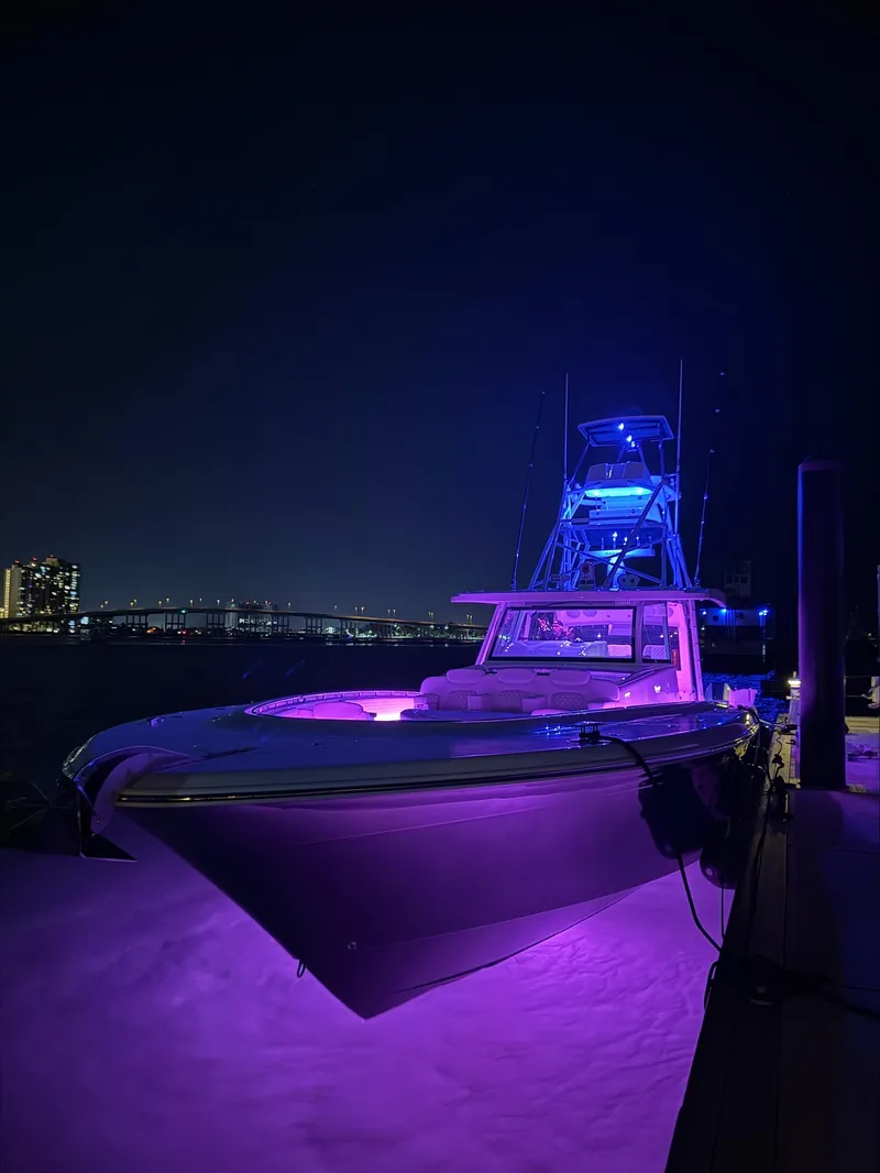 Slide: The Image of 2025 HCB 56 Suenos GIX boat illuminated with purple lights at night. - 17