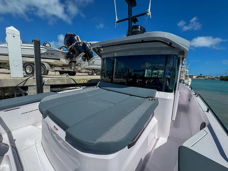 Slide: The Image of 2024 Axopar Sun Top boat docked, featuring sleek design and spacious deck under clear blue sky. - 12