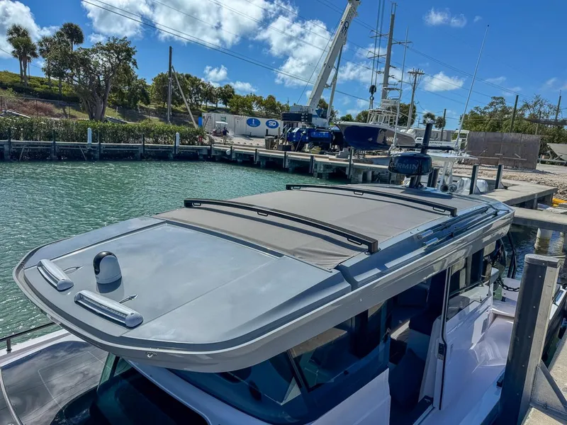 Slide: The Image of 2024 Axopar Sun Top boat docked at marina under clear blue sky. - 14
