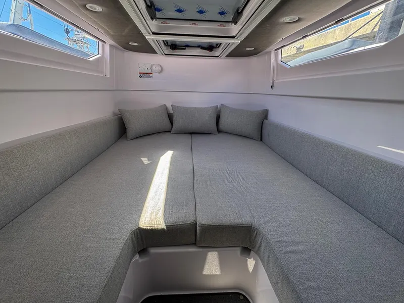 Slide: The Image of 2024 Axopar Sun Top interior cabin with gray cushions and overhead windows. - 22