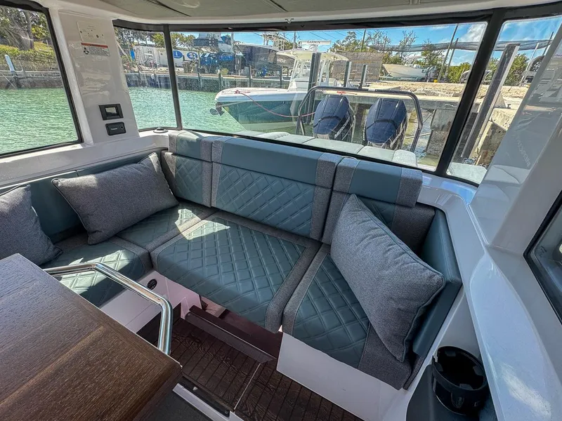 Slide: The Image of 2024 Axopar Sun Top interior with cushioned seating and waterfront view. - 23
