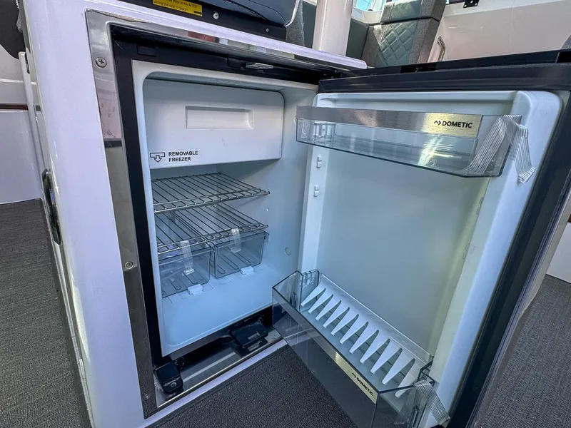 Slide: The Image of Open Dometic fridge inside 2024 Axopar Sun Top boat, showcasing interior storage space. - 24