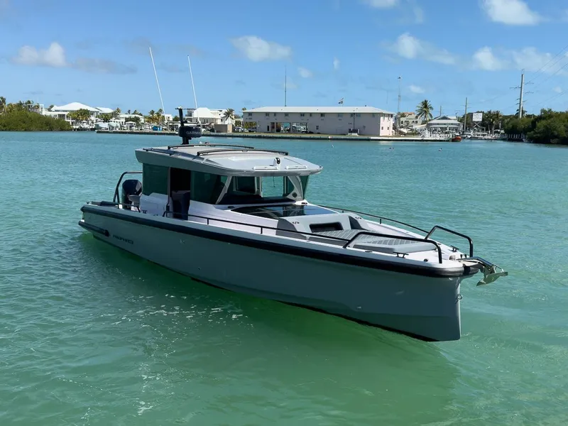 Slide: The Image of 2024 Axopar Sun Top boat on turquoise water, clear sky background. - 8