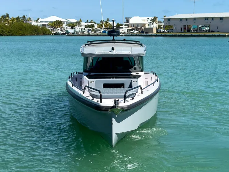Slide: The Image of 2024 Axopar Sun Top boat on turquoise water, front view, near coastal buildings. - 9