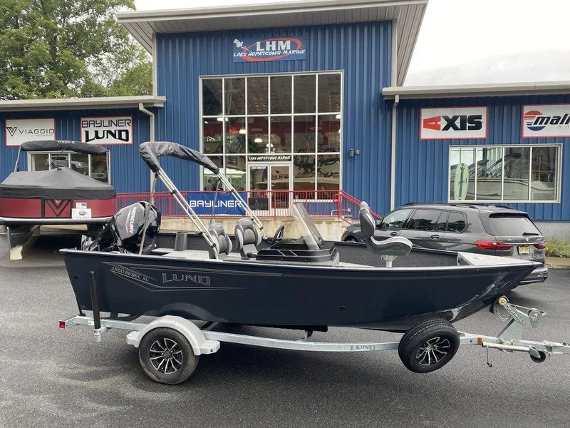 Slide: The Image of 2025 Lund 1650 Rebel XL boat on trailer outside dealership. - 2