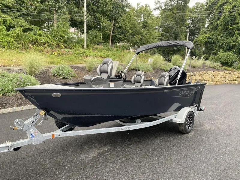 Slide: The Image of 2025 Lund 1650 Rebel XL boat on trailer, parked outdoors with lush greenery background. - 6