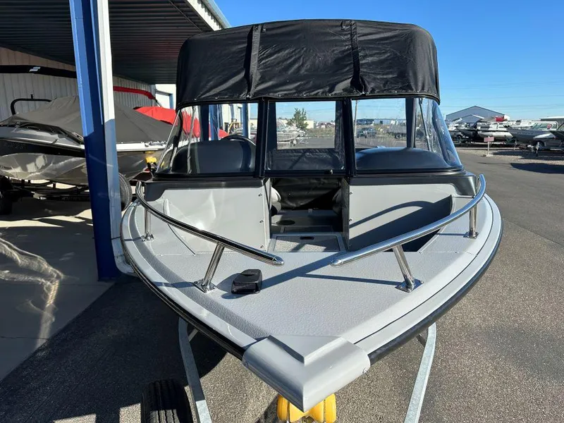 Slide: The Image of 2025 Smoker Craft Osprey 172 boat with black canopy in a marina setting. - 2
