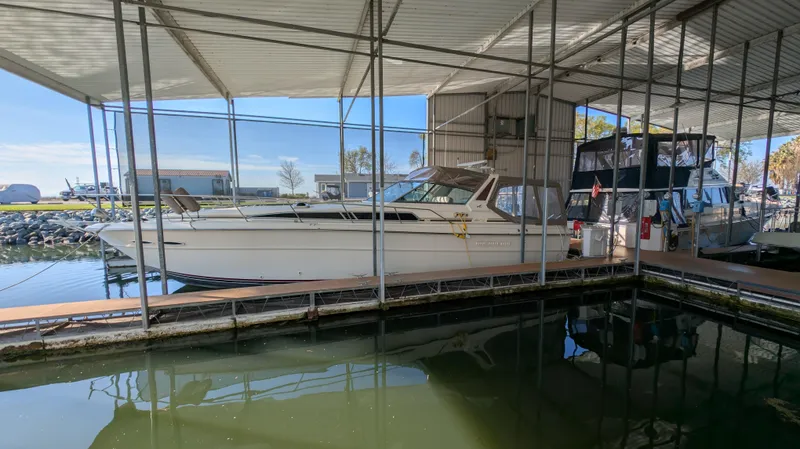 The Image of 1987 Sea Ray 390 Express Cruiser docked in a covered marina. - 0