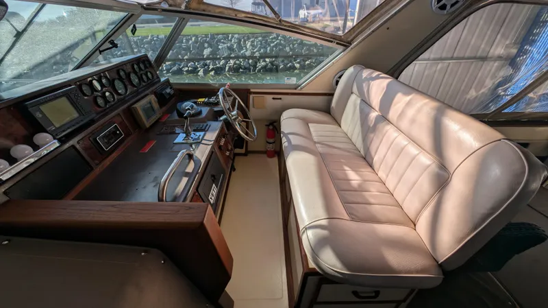 Slide: The Image of 1987 Sea Ray 390 Express Cruiser interior with helm and beige seating. - 10