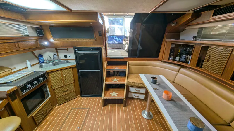 Slide: The Image of 1987 Sea Ray 390 Express Cruiser interior with kitchen, seating, and wooden flooring. - 12