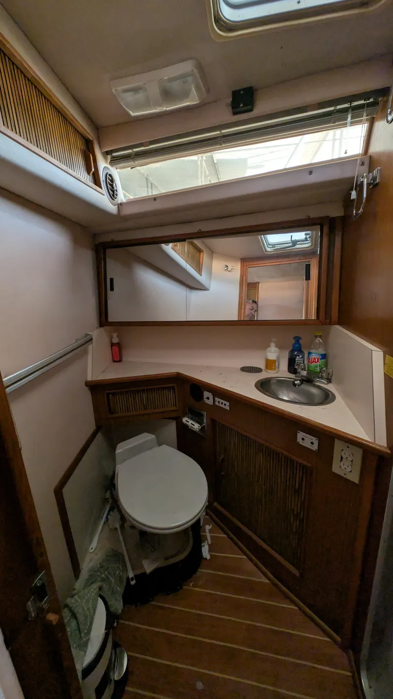Slide: The Image of 1987 Sea Ray 390 Express Cruiser bathroom with sink, toilet, and wooden cabinetry. - 19