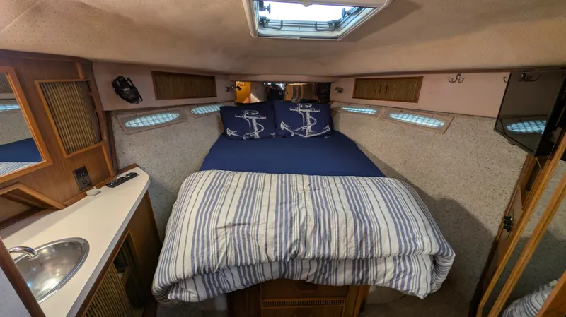 Slide: The Image of 1987 Sea Ray 390 Express Cruiser cabin with bed, striped bedding, and nautical decor. - 21