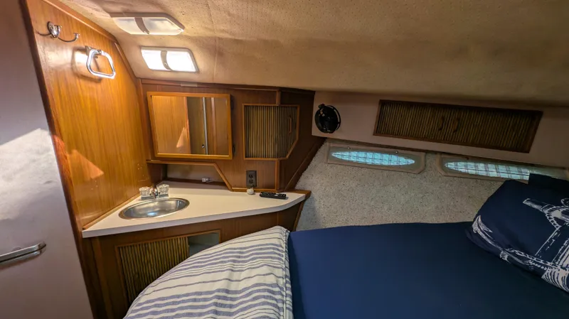 Slide: The Image of 1987 Sea Ray 390 Express Cruiser cabin with bed, sink, and wooden cabinetry. - 22
