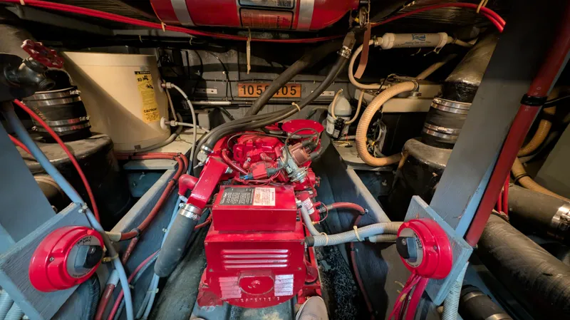 Slide: The Image of Engine room of 1987 Sea Ray 390 Express Cruiser with red machinery and various hoses. - 36