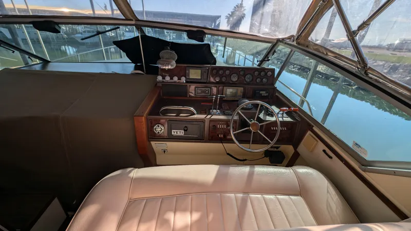 Slide: The Image of 1987 Sea Ray 390 Express Cruiser helm with steering wheel and control panel, docked by the water. - 7