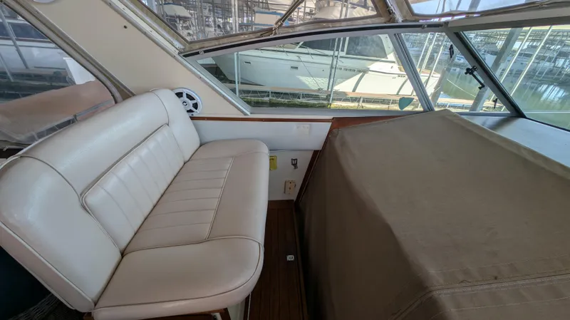 Slide: The Image of 1987 Sea Ray 390 Express Cruiser interior with beige seating and covered dashboard. - 9
