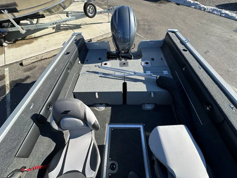 Slide: The Image of 2025 Starweld Fusion 18 DC boat interior with seating and motor, parked outdoors. - 7
