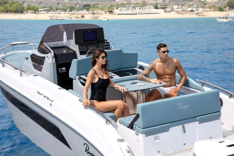Slide: The Image of 2025 Ranieri NEXT 275 LX boat with two people relaxing on deck in sunny weather. - 11