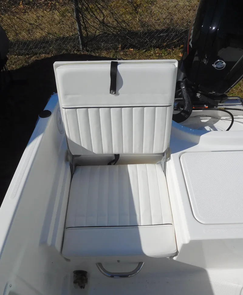 Slide: The Image of 2025 Bayliner Trophy T18Bay boat seat with white upholstery and motor in background. - 29