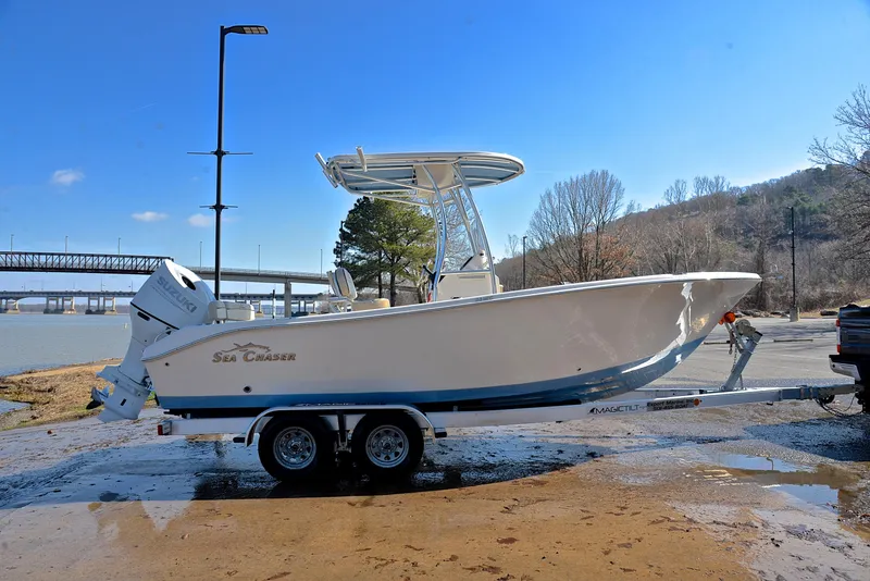 Slide: The Image of 2022 Sea Chaser 22 HFC boat on trailer by a river, clear sky background. - 15