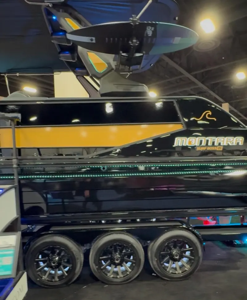 Slide: The Image of 2025 Montara 25' SURF BOSS 2.0 SL boat on display with sleek design and triple-axle trailer. - 33