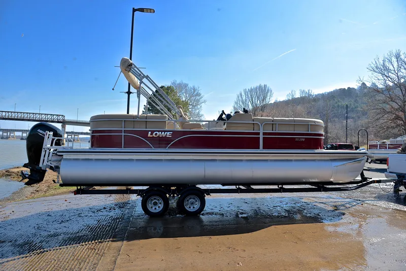 Slide: The Image of 2021 Lowe SS250 pontoon boat on trailer by riverside under clear blue sky. - 15
