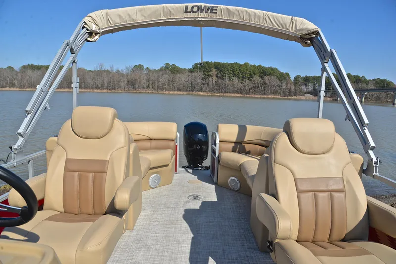 Slide: The Image of 2021 Lowe SS250 pontoon boat with beige seating on a calm lake. - 24