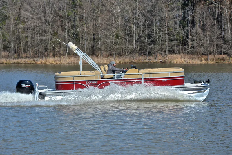 Slide: The Image of 2021 Lowe SS250 pontoon boat cruising on a lake with trees in the background. - 3
