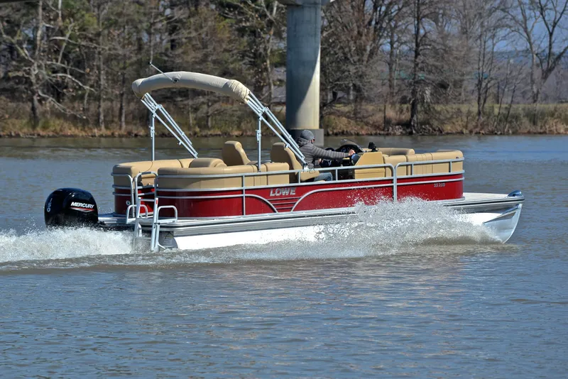 Slide: The Image of 2021 Lowe SS250 pontoon boat cruising on a lake with trees in the background. - 5