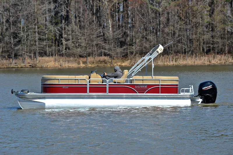 Slide: The Image of 2021 Lowe SS250 pontoon boat cruising on a lake with forest backdrop. - 8