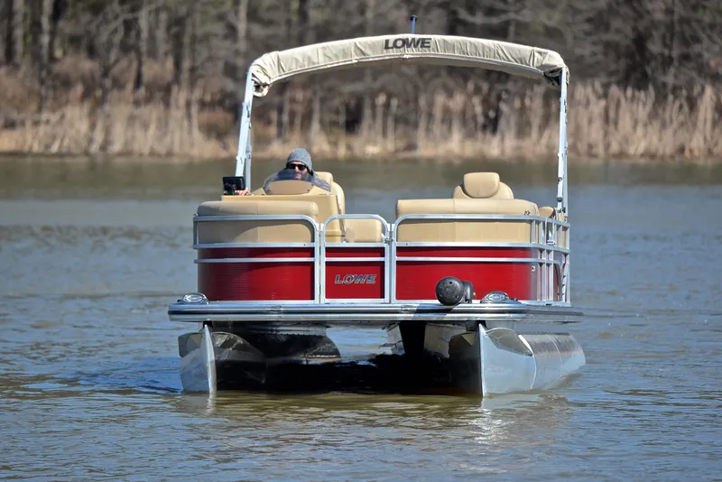 Slide: The Image of 2021 Lowe SS250 pontoon boat on a calm lake, featuring a red and beige design. - 9