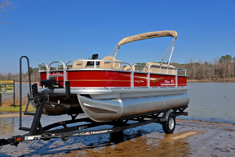 Slide: The Image of 2024 Sun Tracker BASS BUGGY 18 pontoon boat on trailer by a lake. - 10