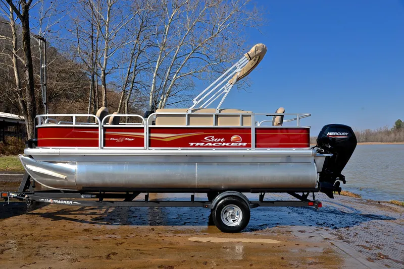 Slide: The Image of 2024 Sun Tracker BASS BUGGY 18 pontoon boat on trailer by a lake. - 11